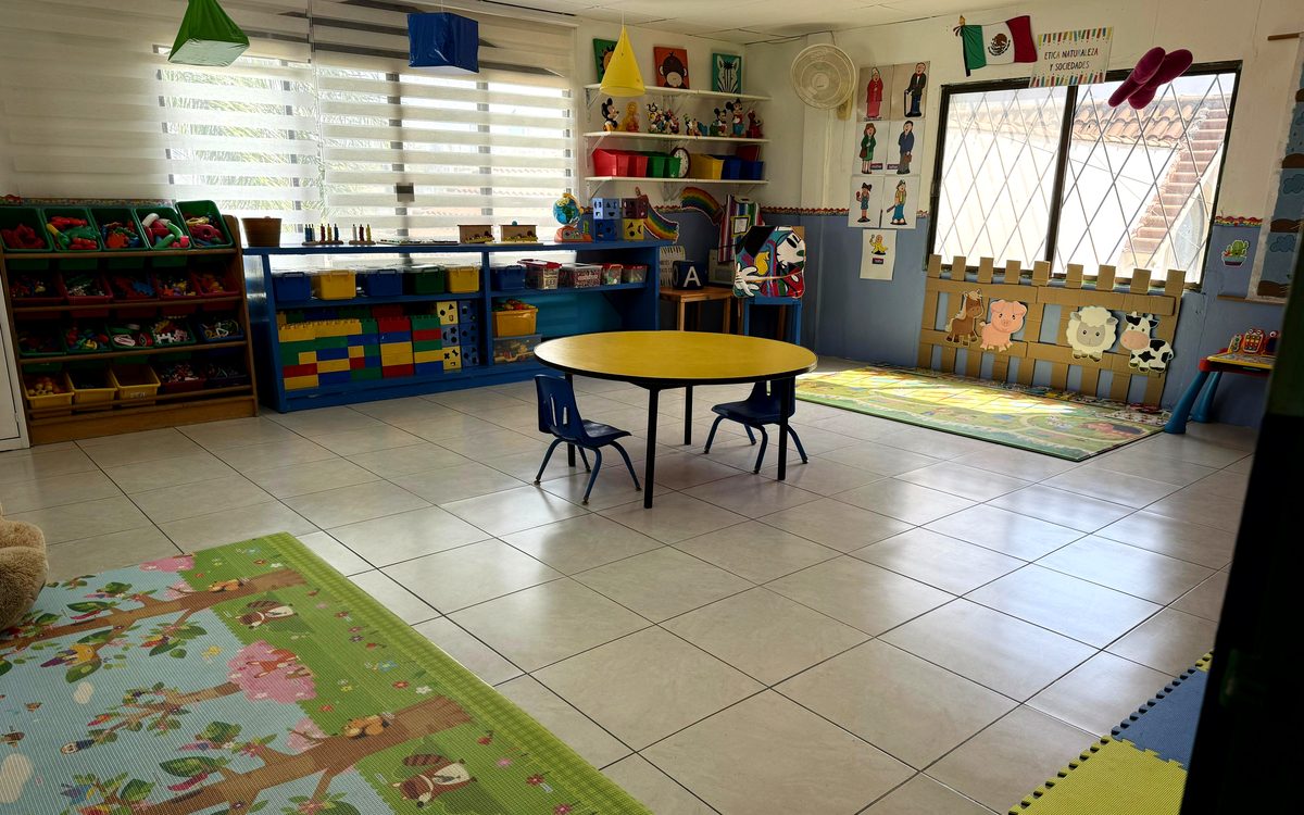 Salón de Kínder Lety con mesa de trabajo, material didáctico y ventanas con luz natural